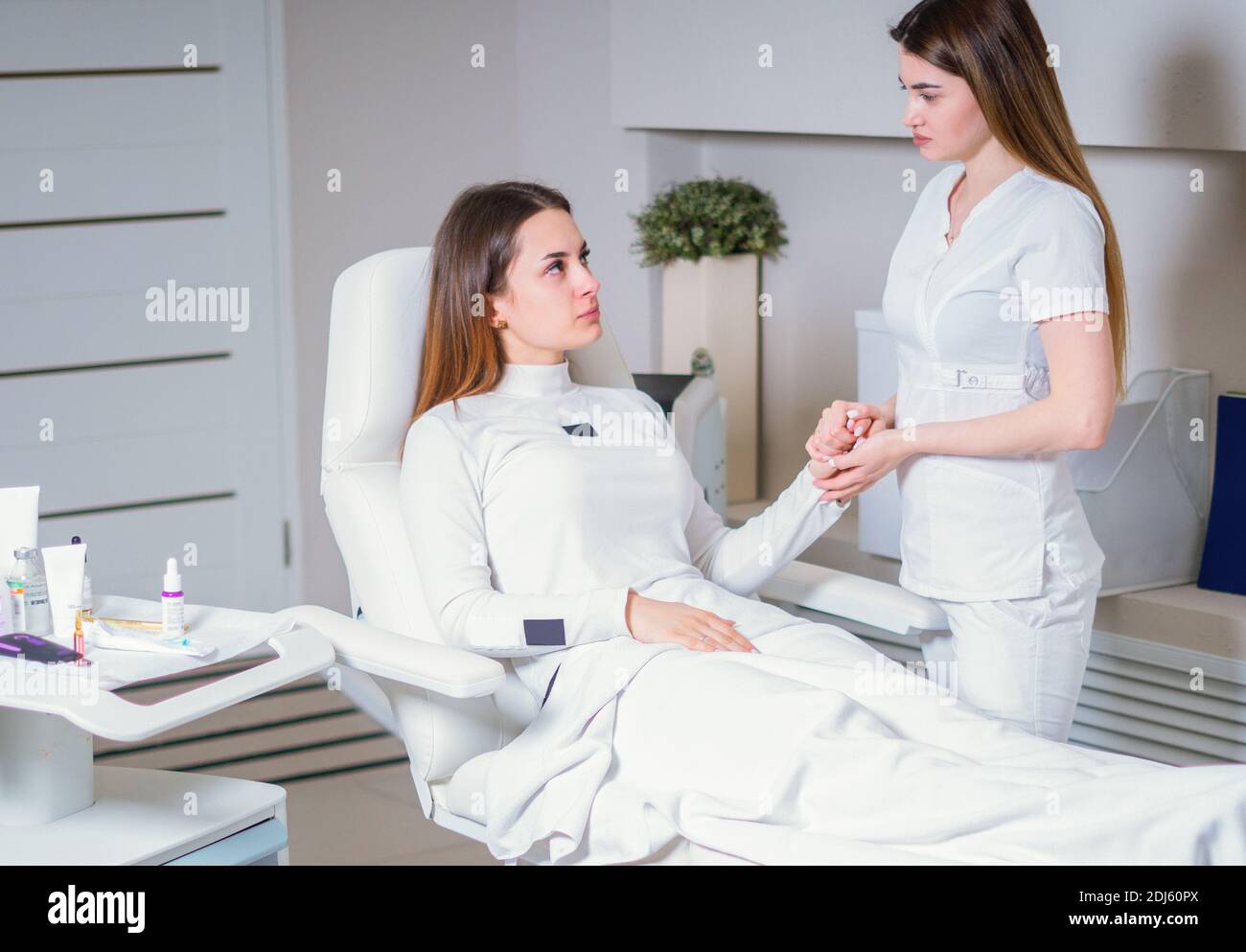 Young pretty woman came to a beauty salon and consults with a beautician on anti-aging treatments. Stock Photo