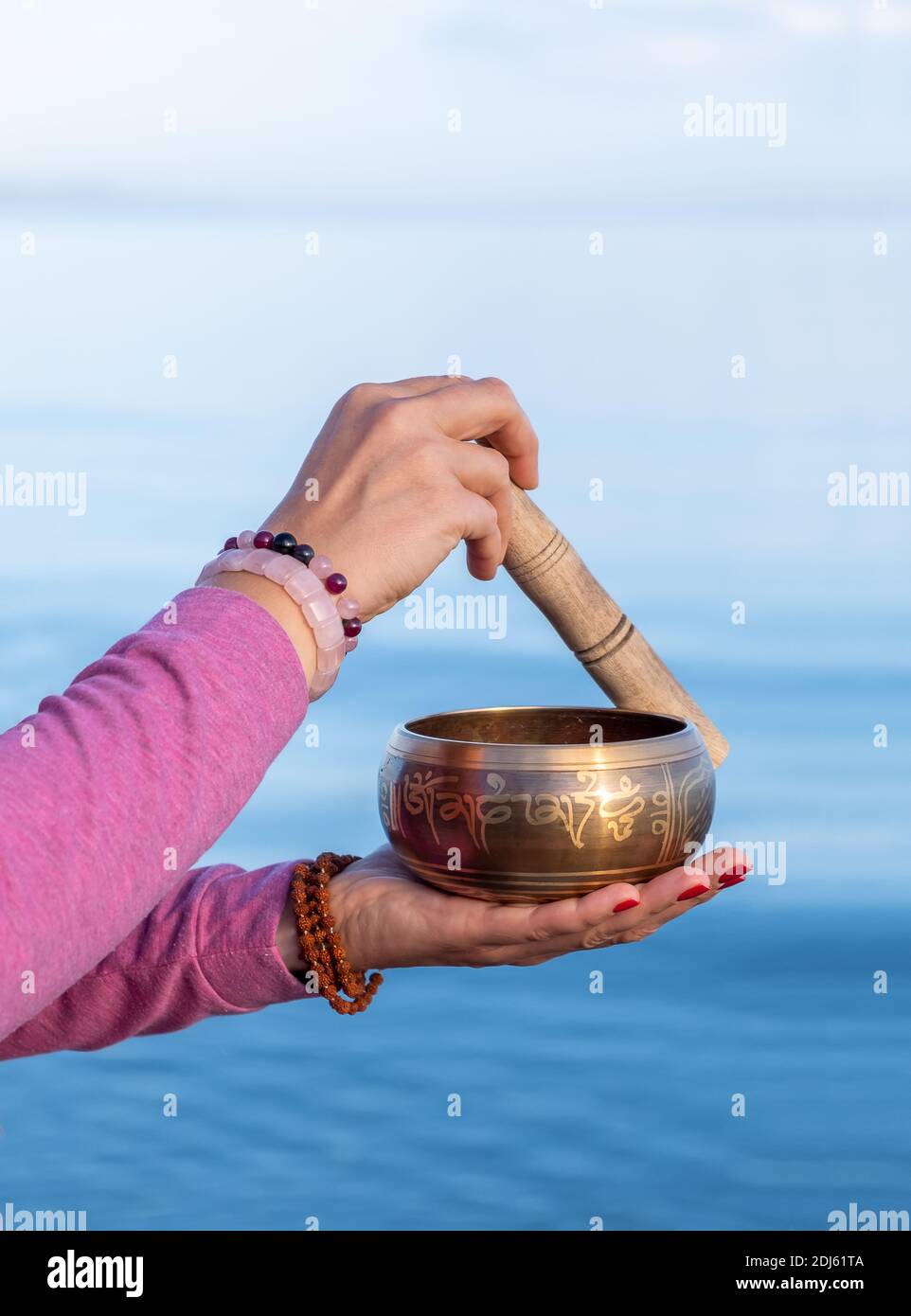 Tibetan singing bowl in female hands against the background of the nature. Stock Photo
