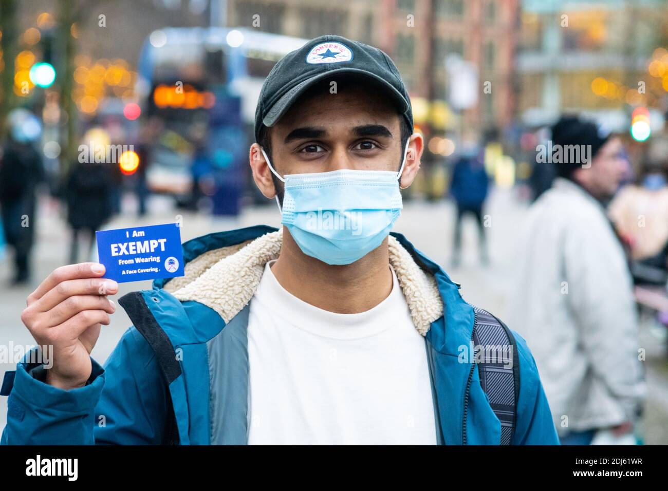 Manchester December 2020. A young man wearing his face mask while on the streets, holding up an exemption card handed to him by a protester Stock Photo