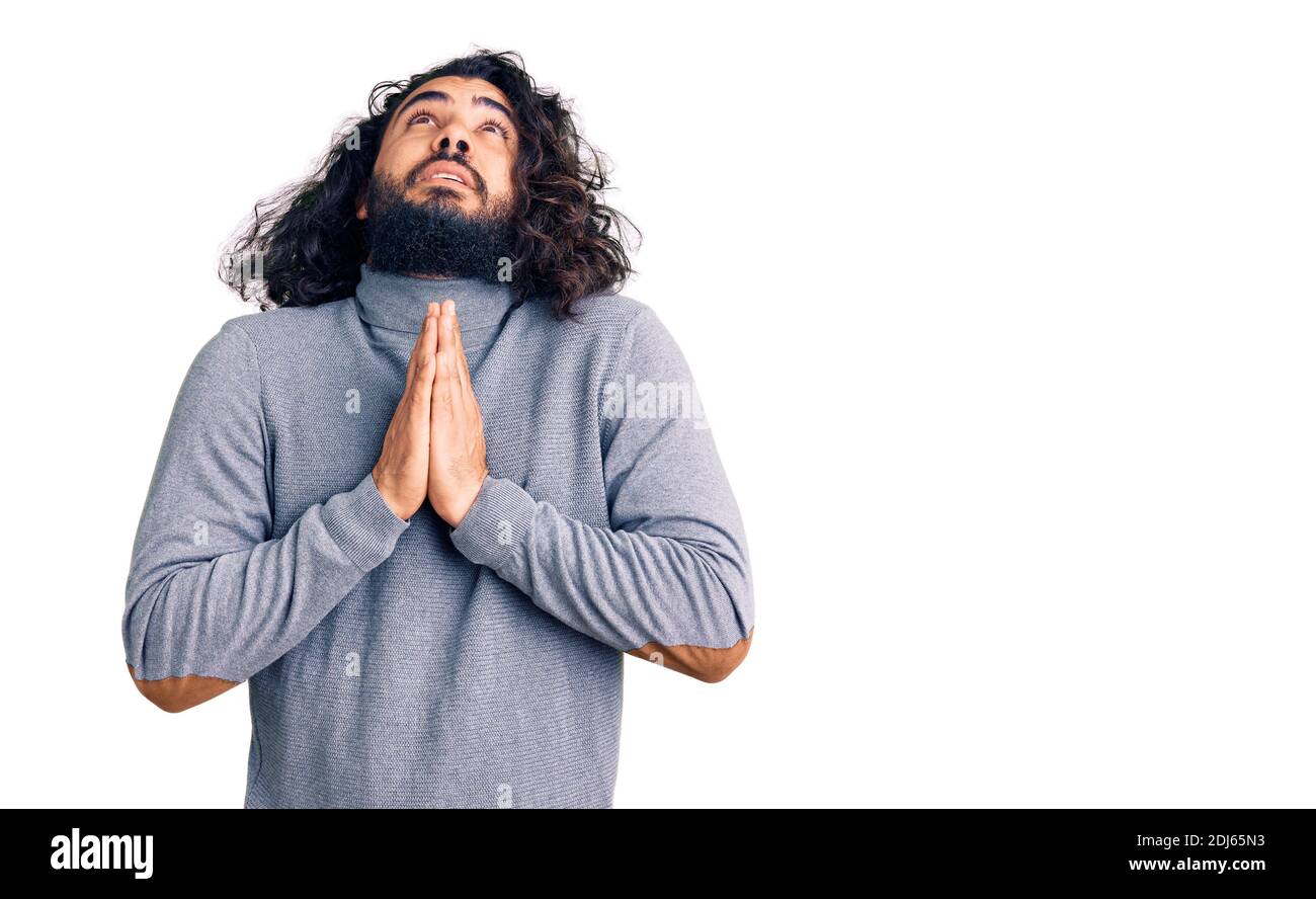 Young arab man wearing casual clothes begging and praying with hands ...