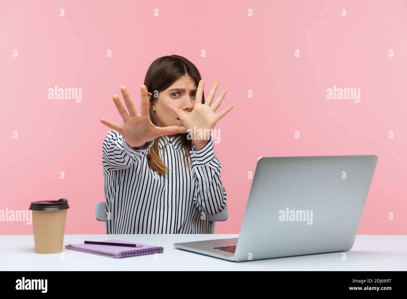 No, I'm scared! Frightened woman with shocked expression raising hands in stop gesture, defending herself, freaked out of troubles working on laptop. Stock Photo