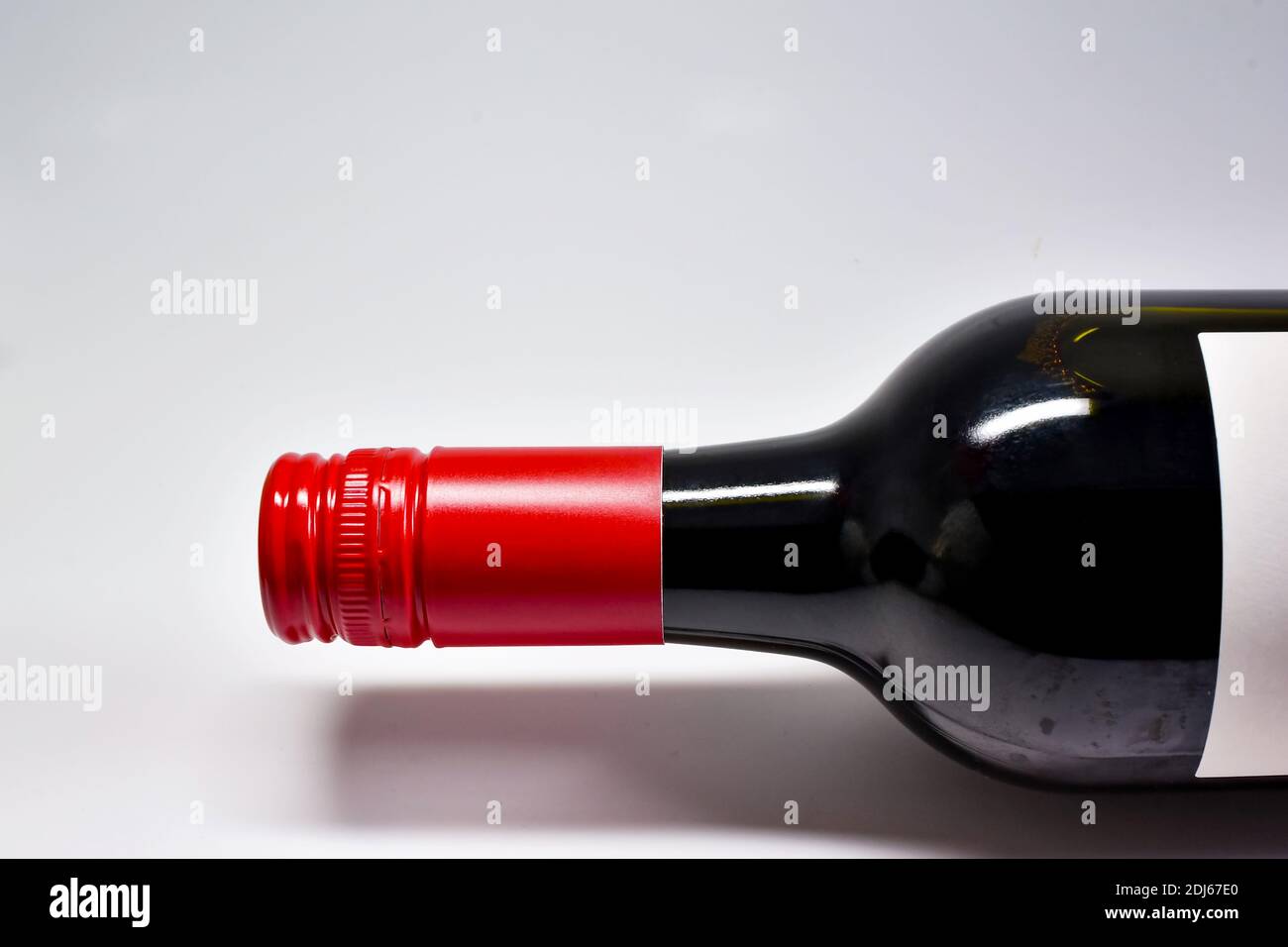 Close up of the top and neck of a screw cap bottle of red wine on a plain white background. No people. Copy space. Stock Photo