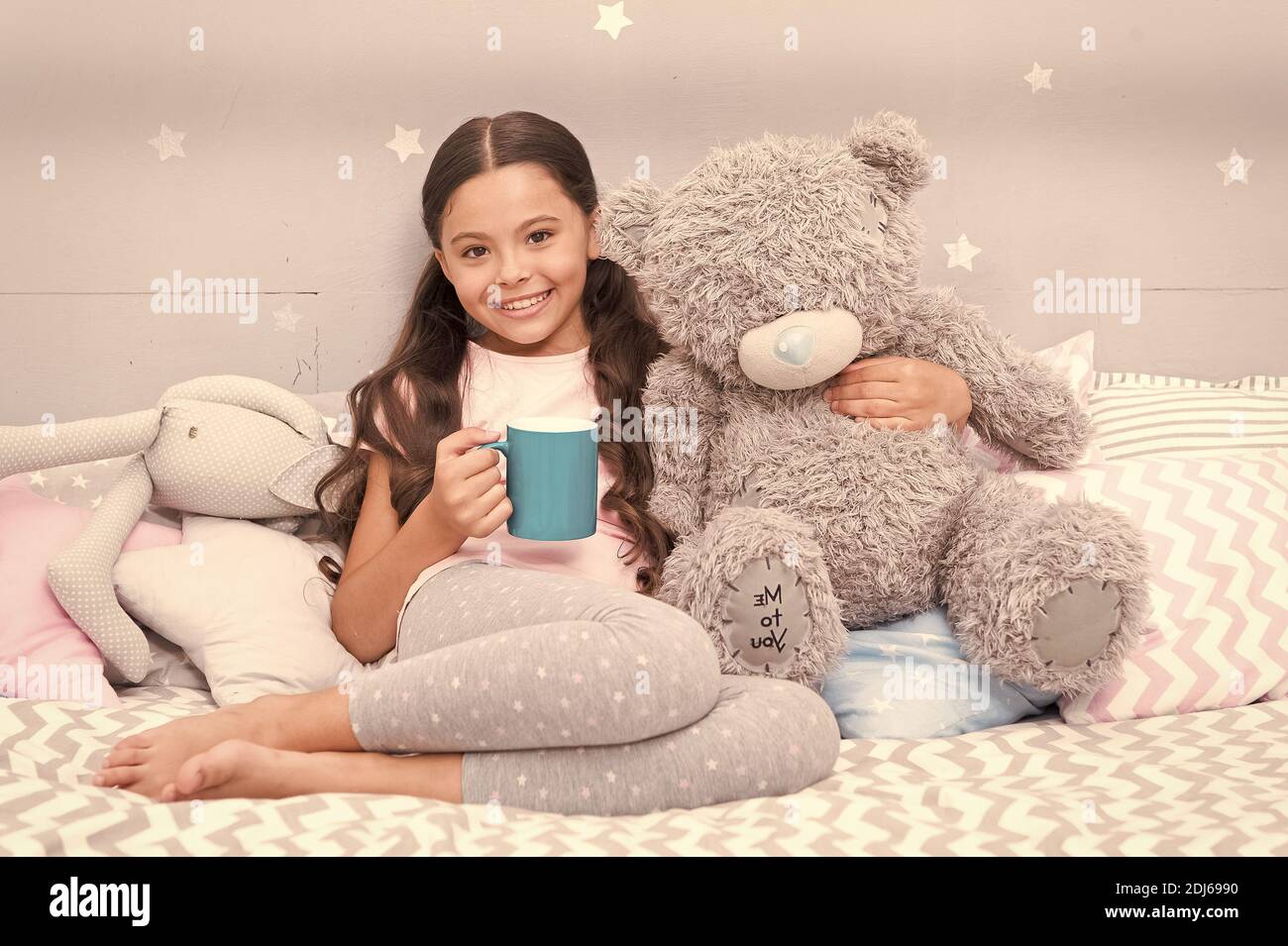 Drinking milk just before bed. Bedtime beverage. Hot milk before sleep. Health Benefits Drinking water before bed. Little child hold mug. Girl in pajamas drinking tea. Relaxation before sleep. Stock Photo