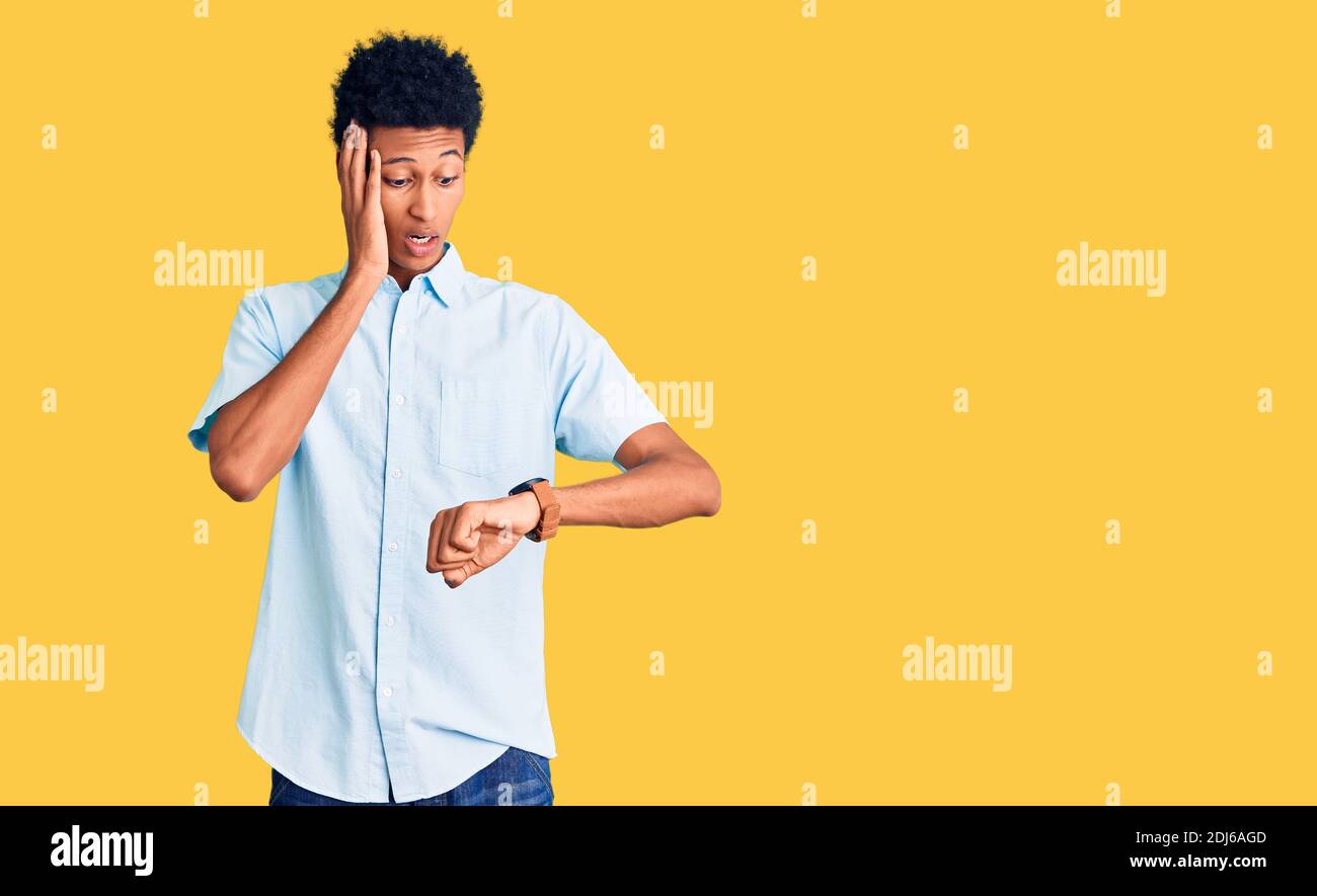 Young african american man wearing casual clothes looking at the watch ...