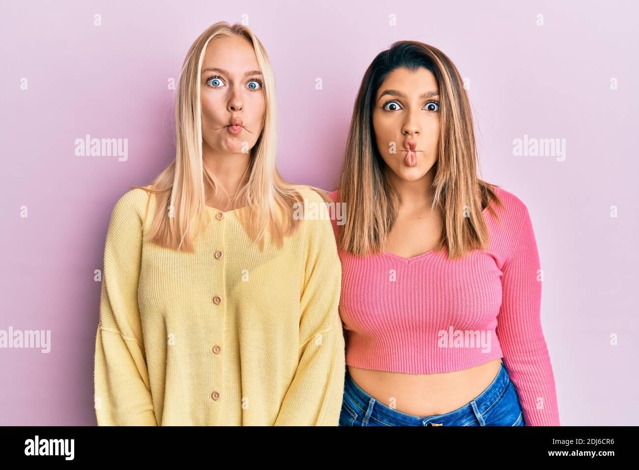 Two friends standing together over pink background making fish face with  lips, crazy and comical gesture. funny expression Stock Photo - Alamy