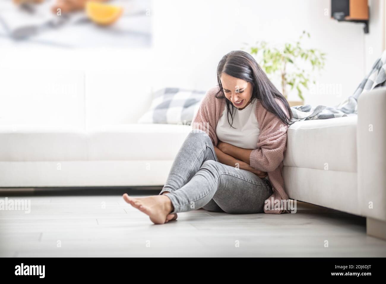 Abdominal pain of a girl sitting on a floor, leaning against