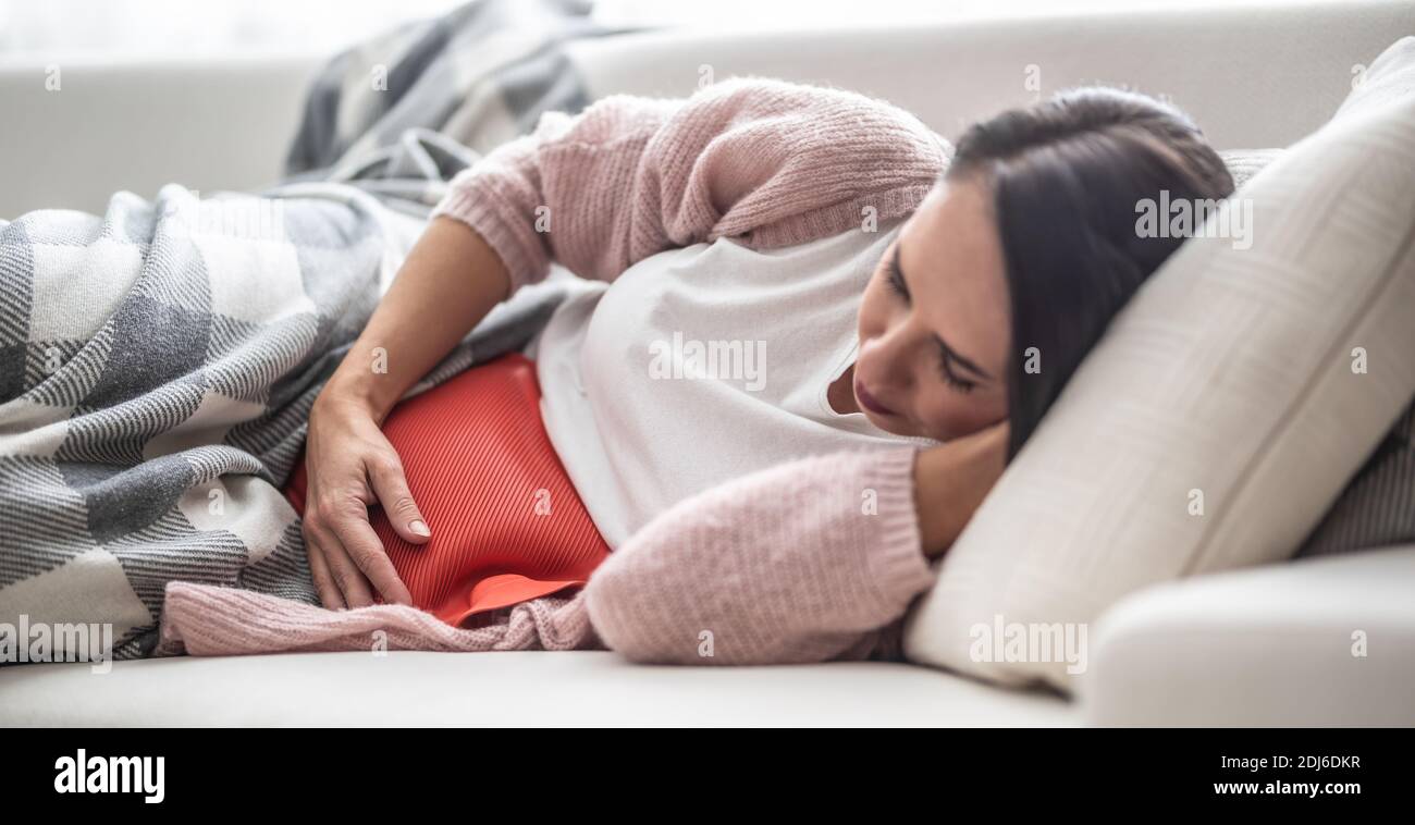 Woman falling asleep under the blanket on a couch after thermophore