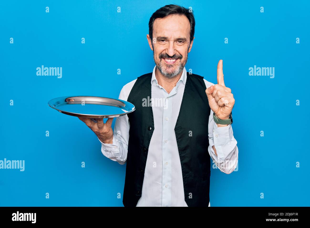 Waitressing Man Middle age handsome waitress man holding tray standing over isolated ...