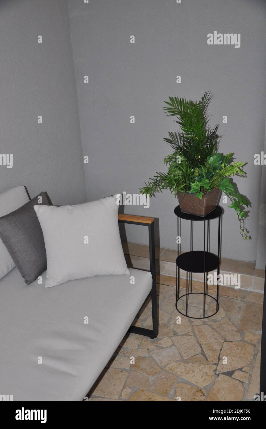 Corner of the balcony with modern two-seater and plant. Illustration of a sofa on a shiny stone floor with a plant. Stock Photo
