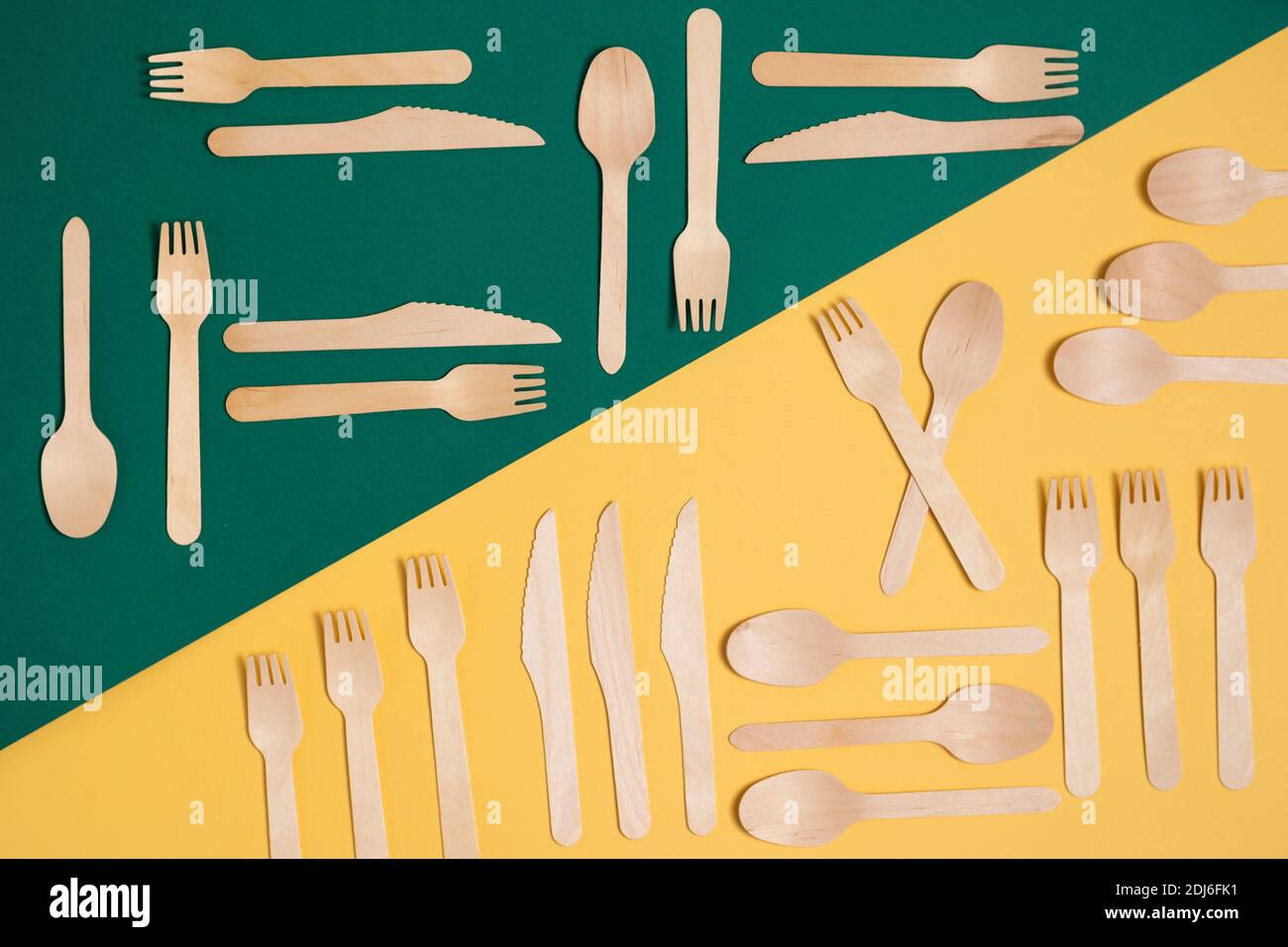 Wooden fork, knife and spoon on a diagonally divided green and yellow