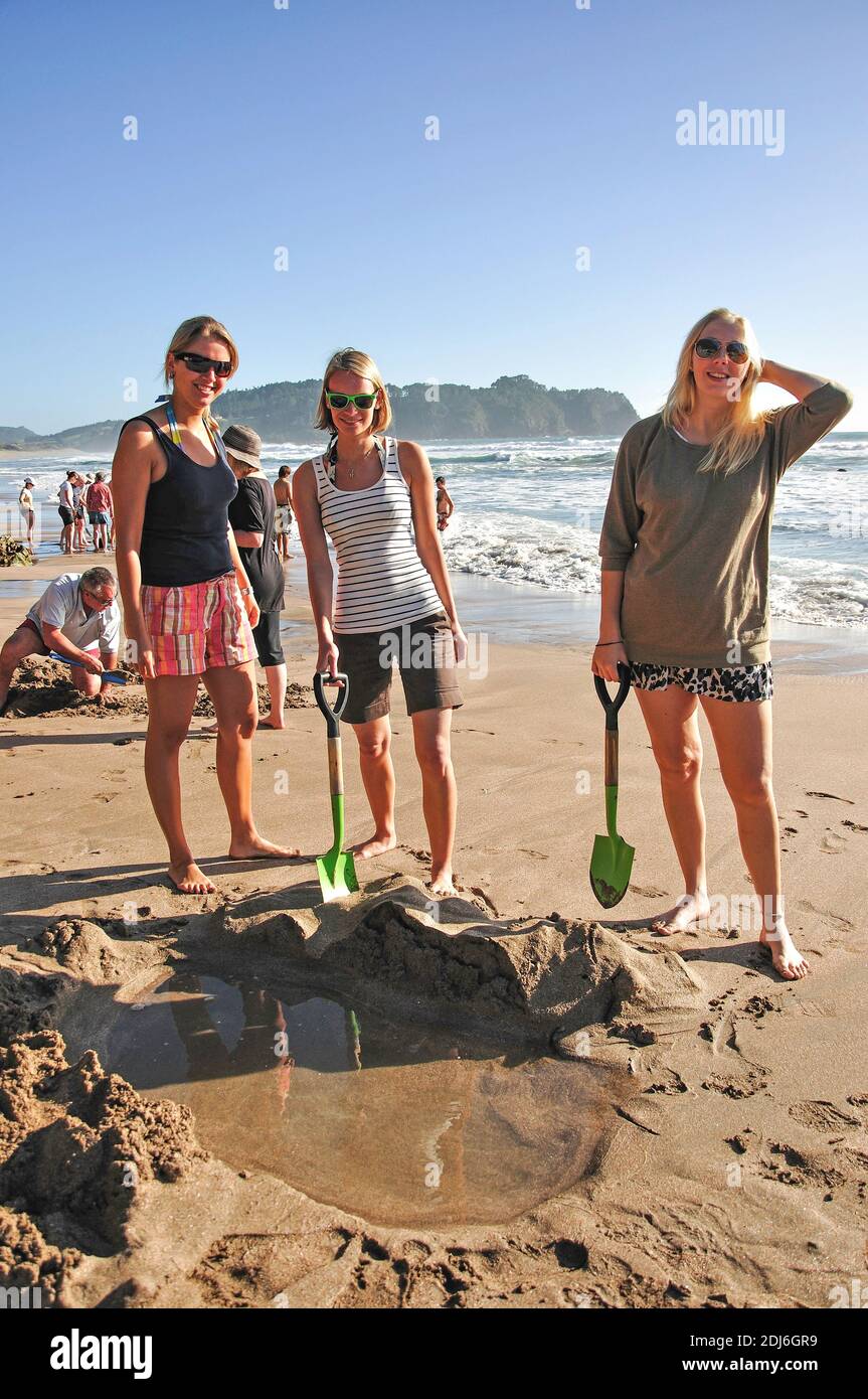 Tourists digging hole in sand for hot water, Hot Water Beach, Mercury Bay, Coromandel Peninsula, Waikato Region, New Zealand Stock Photo