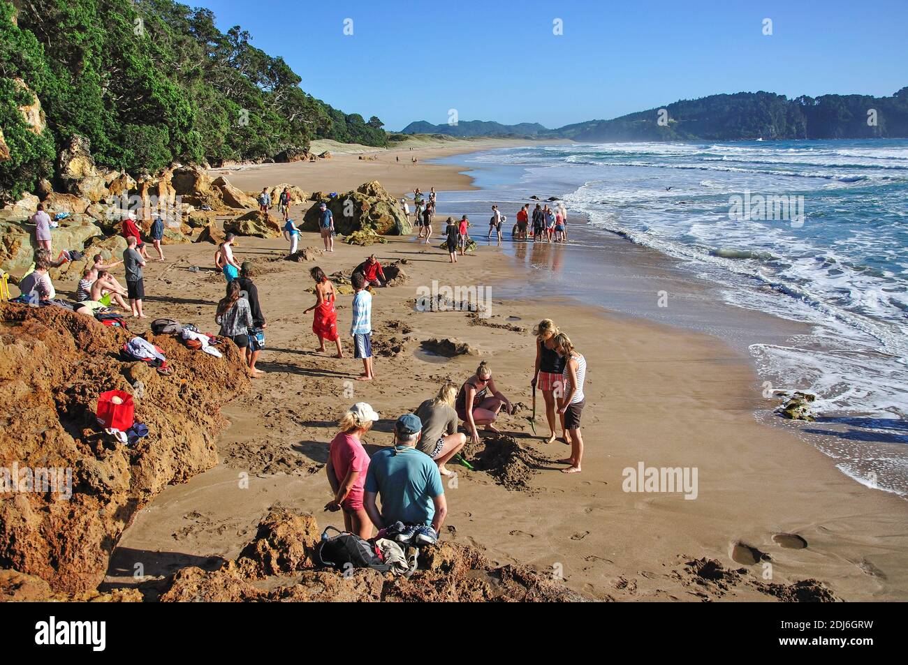 Tourists digging hole in sand for hot water, Hot Water Beach, Mercury Bay, Coromandel Peninsula, Waikato Region, New Zealand Stock Photo