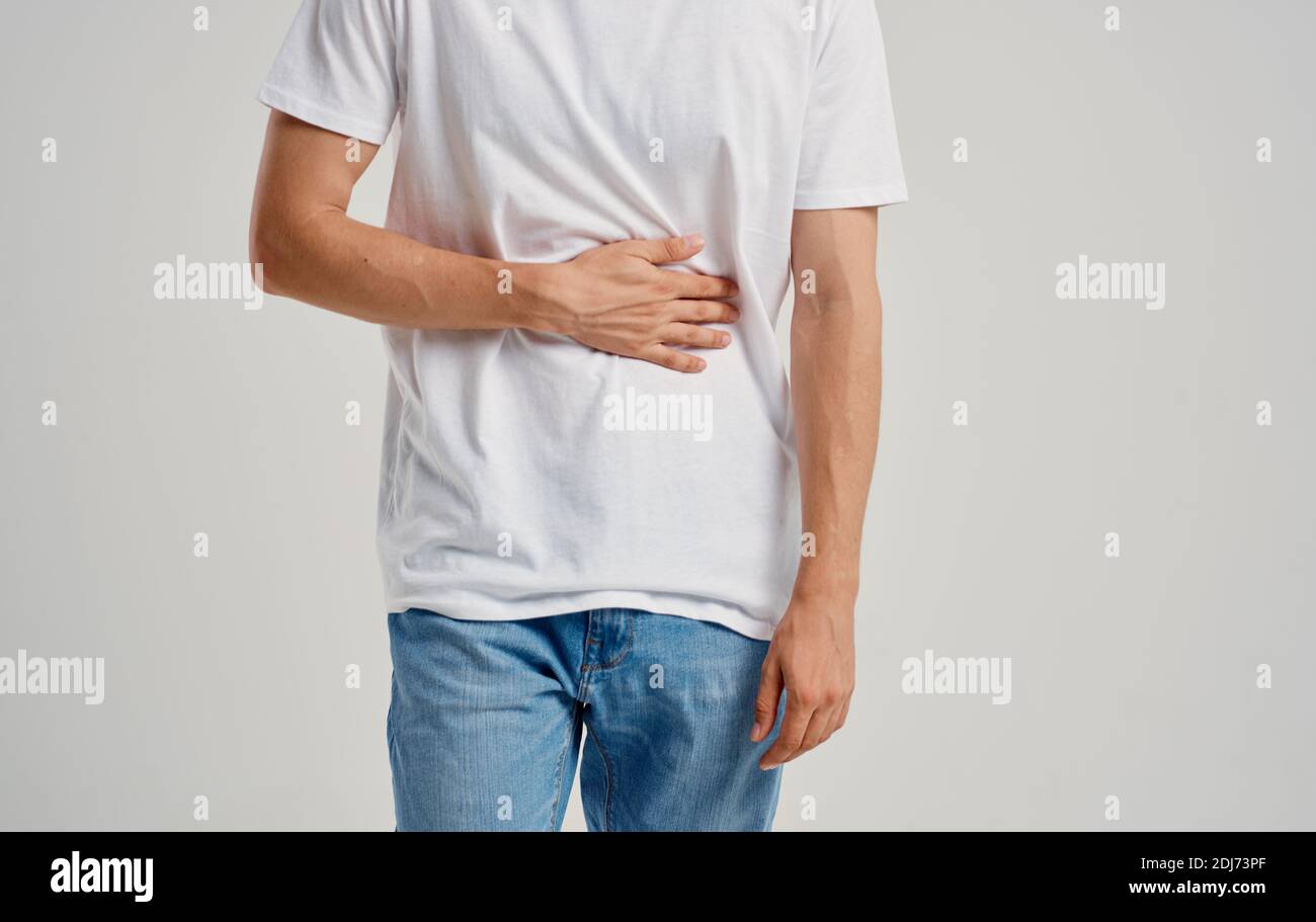 man in white tshirt and jeans touching his stomach with his hands