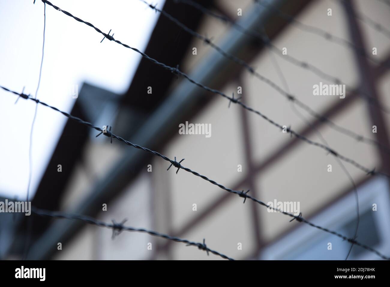 Barbed wire with house in background. Shallow depth of field. Focus on foreground. Stock Photo