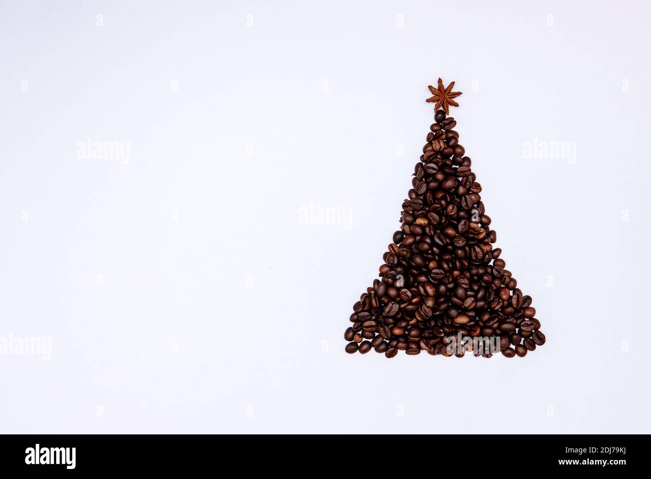 Christmas tree made of coffee beans with anise star on top. Minimal Christmas background Stock Photo