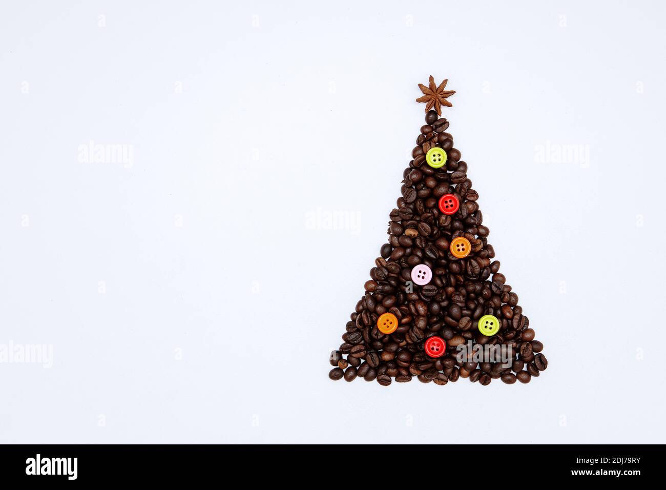 Christmas tree made of coffee beans with anise star on top and colorful buttons as decoration. Minimal Christmas background Stock Photo