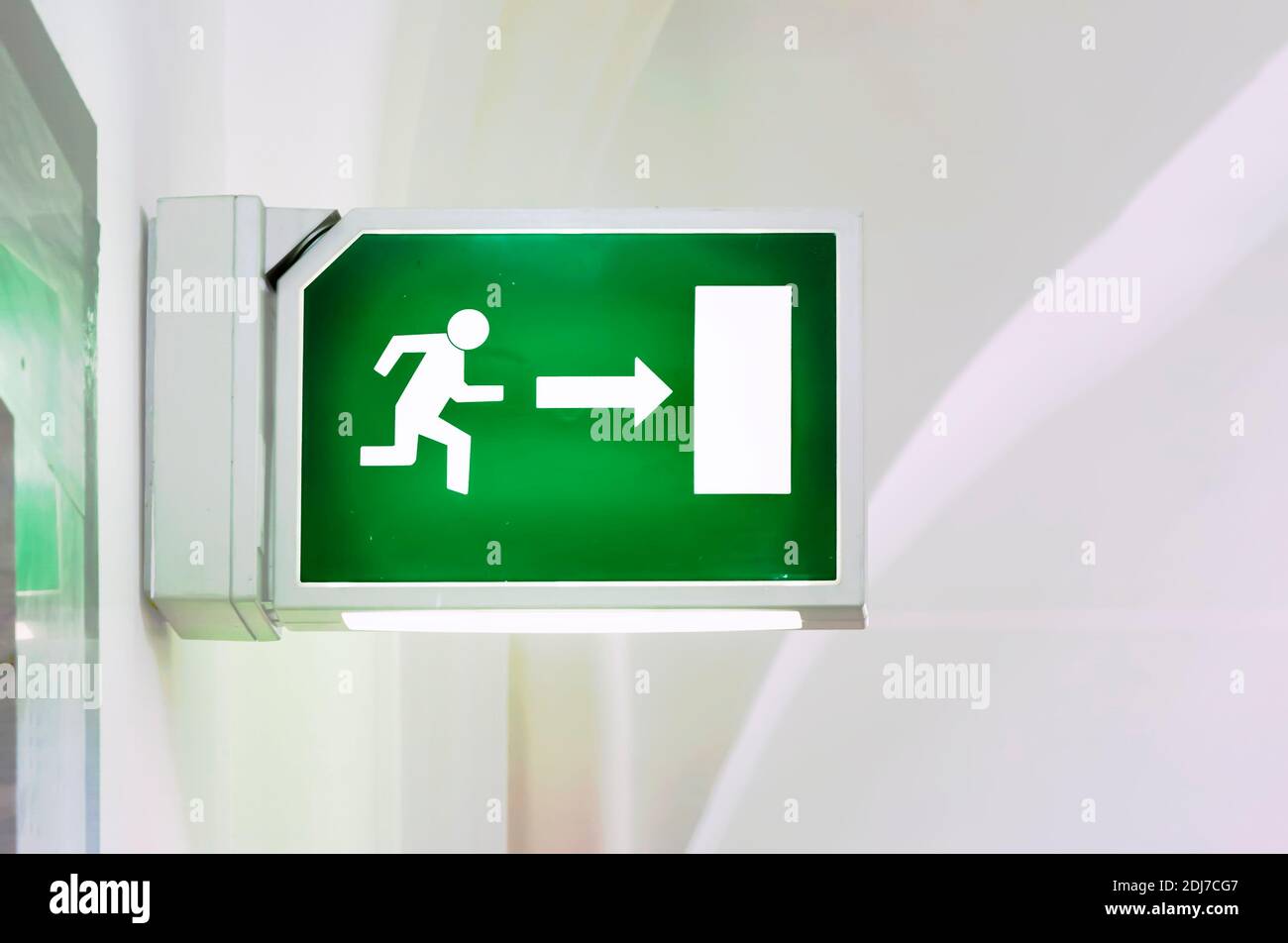 Illuminated green emergency exit sign. Stylized human figure running towards a door. Security and infographics Stock Photo