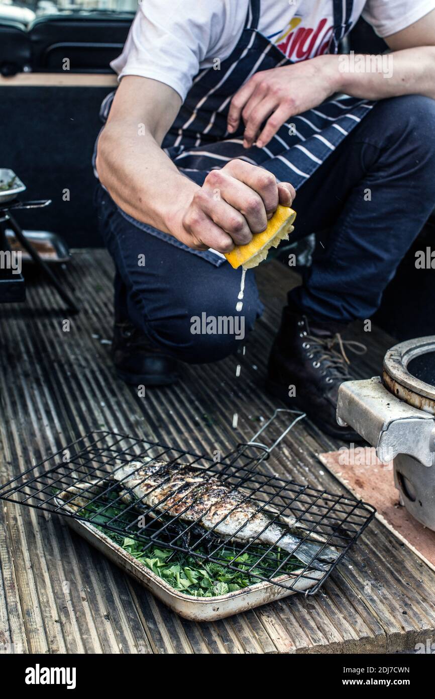 GREAT BRITAIN / England / London /Young man is grilling fresh fish out of the back of a Land Rover in London Stock Photo