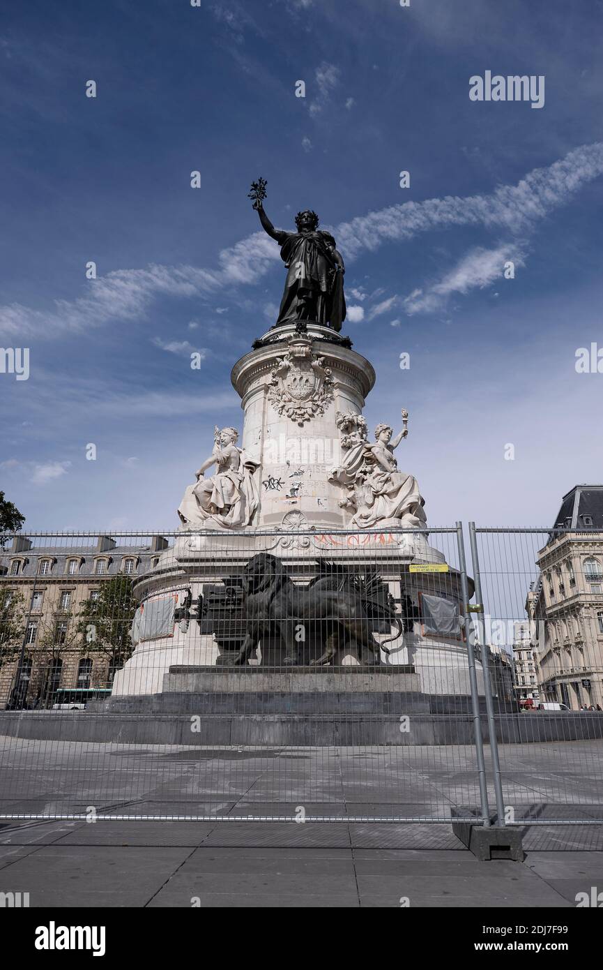 People walk by city employees as they clean graffitis of the statue of Place de la Republique in Paris, on August 2, 2016 which had become a makeshift memorial in tribute to the victims of the recent attacks of the last two years. The City of Paris began on August 1, 2016 a large cleaning operation of the statue in the center of the square of the Republic, whose pedestal has become after each terrorist attack where people deposited flowers, candles or poems in tribute and support. Archivists of the city, as they have done several times in recent months, had to first select the last objects or Stock Photo