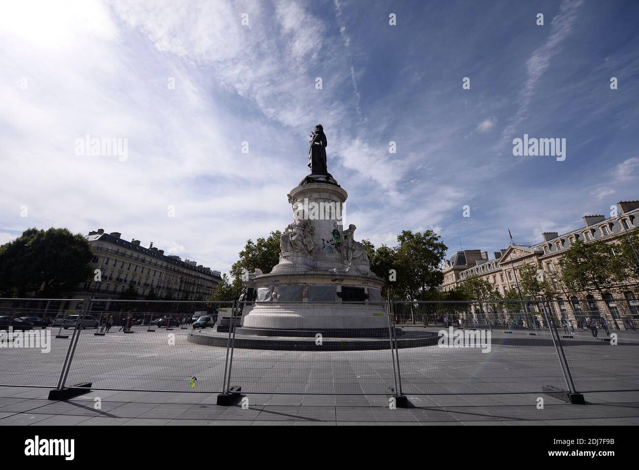 People walk by city employees as they clean graffitis of the statue of Place de la Republique in Paris, on August 2, 2016 which had become a makeshift memorial in tribute to the victims of the recent attacks of the last two years. The City of Paris began on August 1, 2016 a large cleaning operation of the statue in the center of the square of the Republic, whose pedestal has become after each terrorist attack where people deposited flowers, candles or poems in tribute and support. Archivists of the city, as they have done several times in recent months, had to first select the last objects or Stock Photo