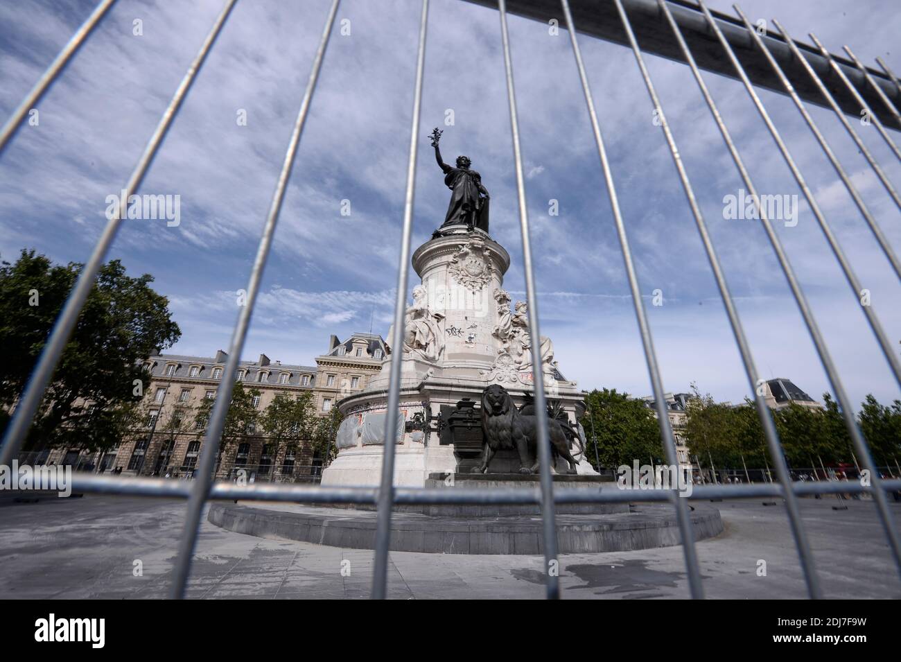 People walk by city employees as they clean graffitis of the statue of Place de la Republique in Paris, on August 2, 2016 which had become a makeshift memorial in tribute to the victims of the recent attacks of the last two years. The City of Paris began on August 1, 2016 a large cleaning operation of the statue in the center of the square of the Republic, whose pedestal has become after each terrorist attack where people deposited flowers, candles or poems in tribute and support. Archivists of the city, as they have done several times in recent months, had to first select the last objects or Stock Photo