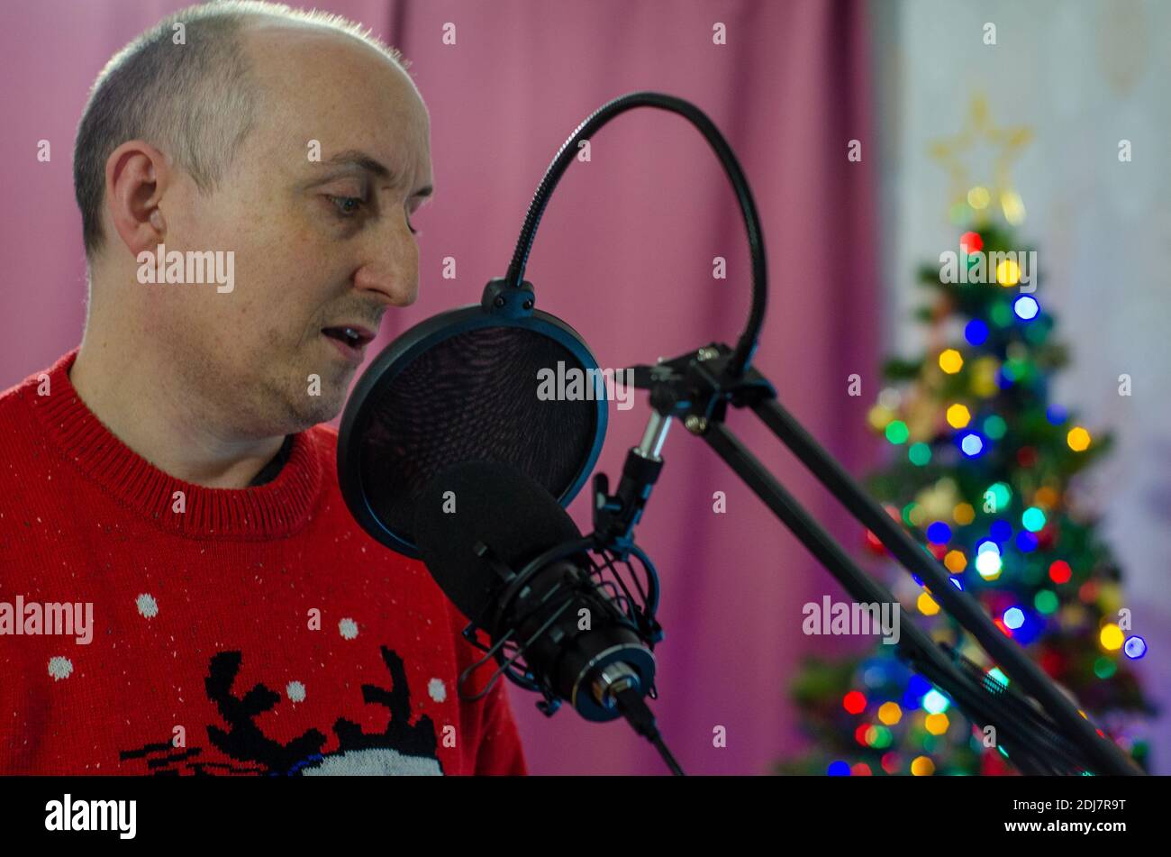 A man singing into a microphone to record some vocals. Stock Photo