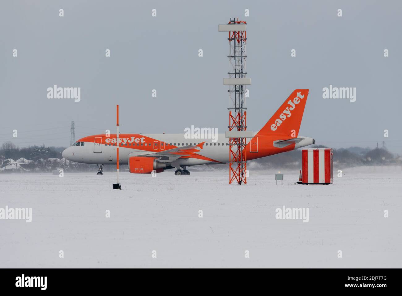 Snow covered London Southend Airport, Essex, UK with an easyJet jet airliner plane taxiing out for take off surrounded by snow passing vital equipment Stock Photo