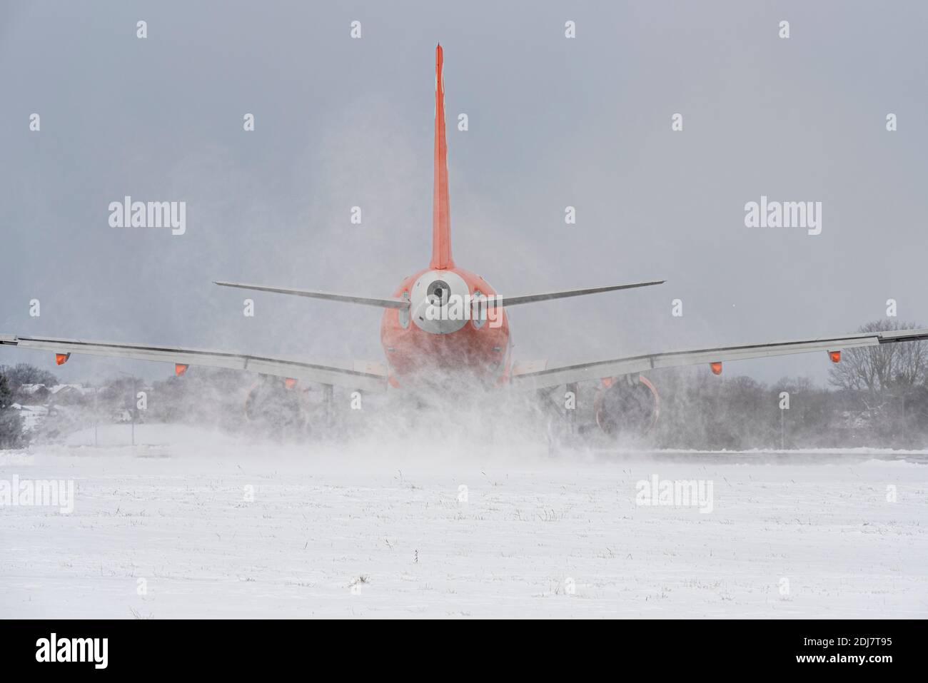 Snow covered London Southend Airport, Essex, UK, with an easyJet jet airliner plane taxiing out for take off surrounded by snow. Jetwash kicking up Stock Photo