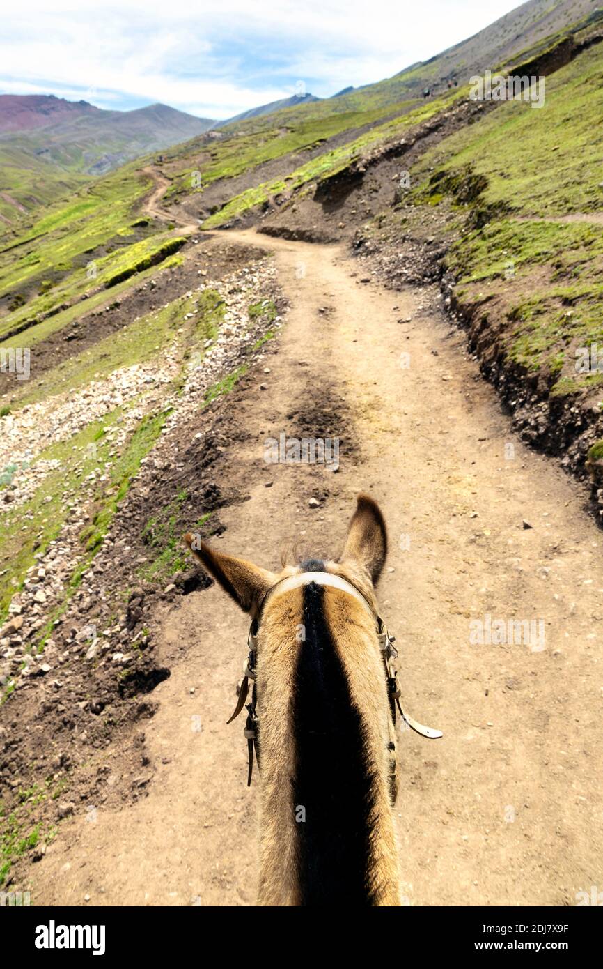 Riding a horse along the Cusipata trail leading up to the Rainbow Mountain (Vinicunca), Peru Stock Photo