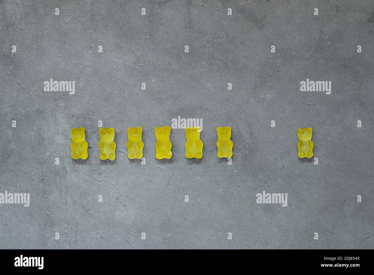 Yellow gummy bears on concrete background. Color of the year 2021 is ultimate gray and illuminating. Stock Photo