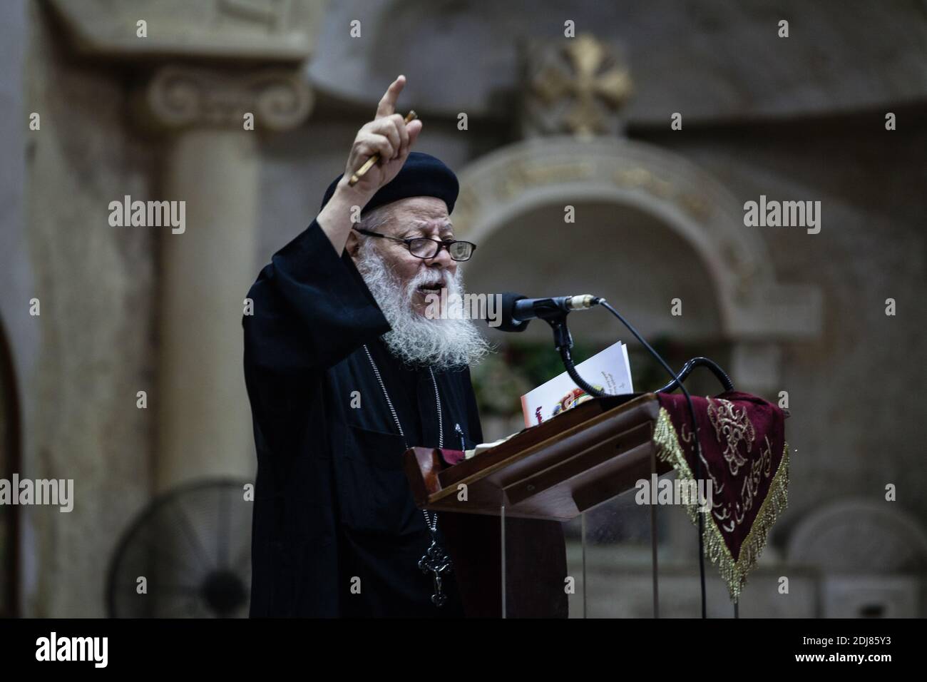 NO WEB/NO APPS - Coptic priest Father Samaan Ibrahim reads his sermon at the Saint Samaan (Simon) Church also known as the Cave Church in the Mokattam village, nicknamed as “Garbage City,” in Cairo, Egypt on August 19, 2016. Once a week hundreds of Muslims gather at the church after the prayer, to attend a session of exorcism performed by the priest. With a cross and holy water he fights spiritual entities and demons. The Monastery has an amphitheater with a seating capacity of 20,000 making it the largest Christian church in the Middle East. It is named after the Coptic Saint, Simon the Tanne Stock Photo