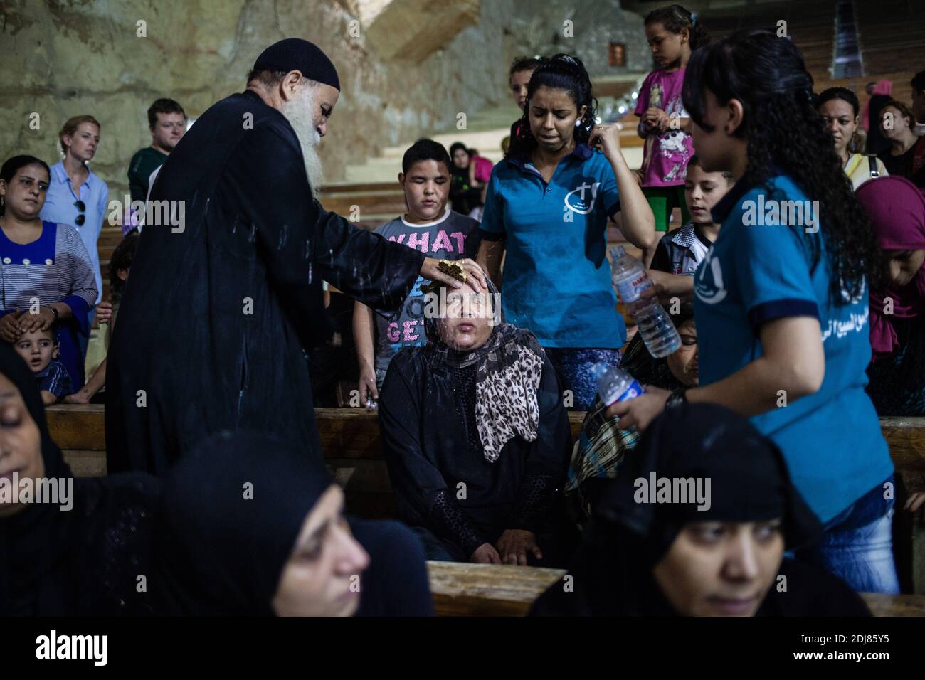 NO WEB/NO APPS - Coptic priest Father Samaan Ibrahim performs an exorcism session at the Saint Samaan (Simon) Church also known as the Cave Church in the Mokattam village, nicknamed as “Garbage City,” in Cairo, Egypt on August 19, 2016. Once a week hundreds of Muslims gather at the church after the prayer, to attend a session of exorcism performed by the priest. With a cross and holy water he fights spiritual entities and demons. The Monastery has an amphitheater with a seating capacity of 20,000 making it the largest Christian church in the Middle East. It is named after the Coptic Saint, Sim Stock Photo