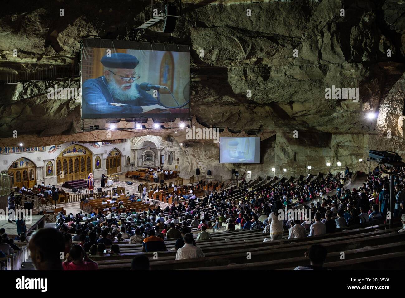 NO WEB/NO APPS - Worshippers attend a service as Coptic priest Father Samaan Ibrahim reads his sermon at the Saint Samaan (Simon) Church also known as the Cave Church in the Mokattam village, nicknamed as “Garbage City,” in Cairo, Egypt on August 19, 2016. Once a week hundreds of Muslims gather at the church after the prayer, to attend a session of exorcism performed by the priest. With a cross and holy water he fights spiritual entities and demons. The Monastery has an amphitheater with a seating capacity of 20,000 making it the largest Christian church in the Middle East. It is named after t Stock Photo