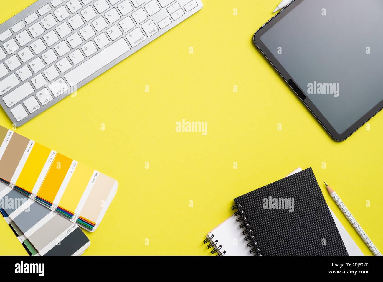 Graphic designer workspace top view with tablet, computer keyboard, RAL color palette, notebook on yellow background. Flat lay, overhead. Creative pro Stock Photo