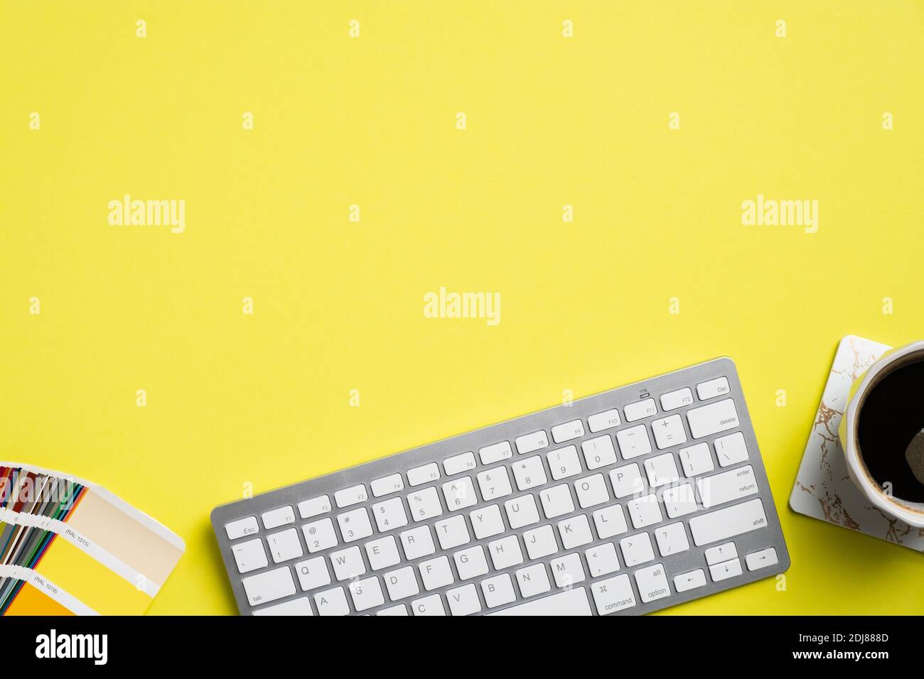 Graphic designer desk top view with computer keyboard, color palette, cup of coffee on yellow background. Flat lay, view from above. Creative professi Stock Photo