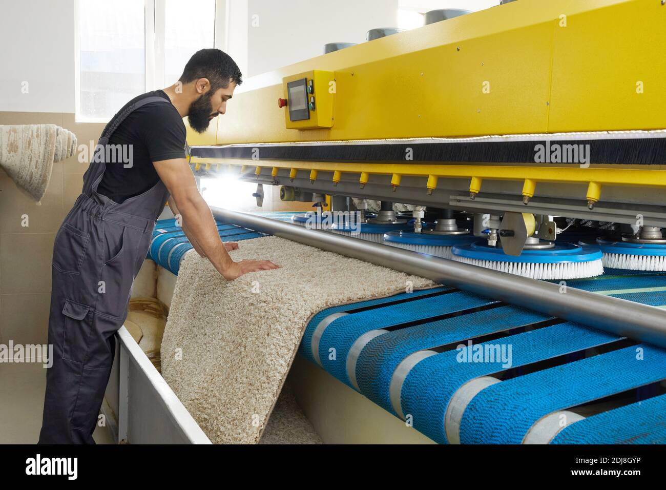 Man operating carpet automatic washing machine in professional laundry service Stock Photo