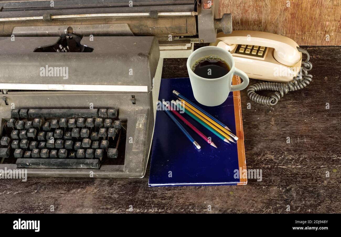 Vintage typewriter ,blue  book,  ,pencil and old telephone on old wooden touch-up in still life concept Stock Photo