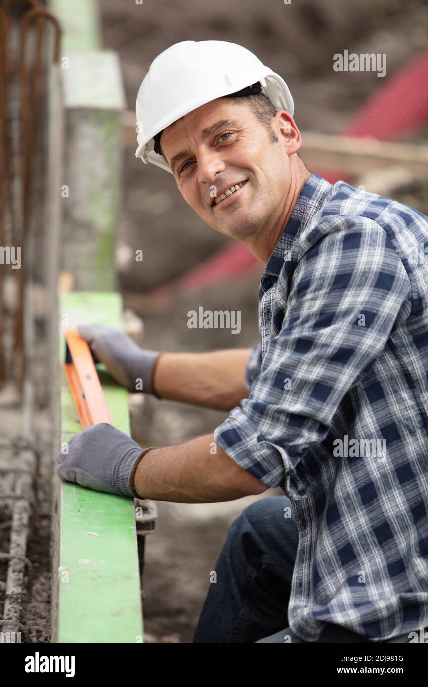 smiling builder using a spirit level on a construction site Stock Photo