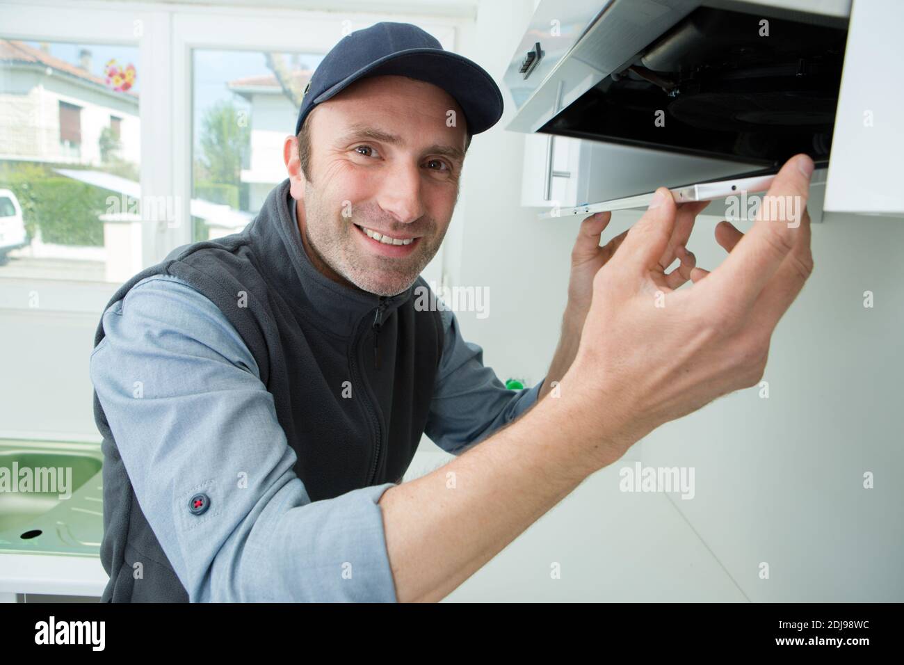 portrait of handyman fixing kitchen exhaust Stock Photo Alamy