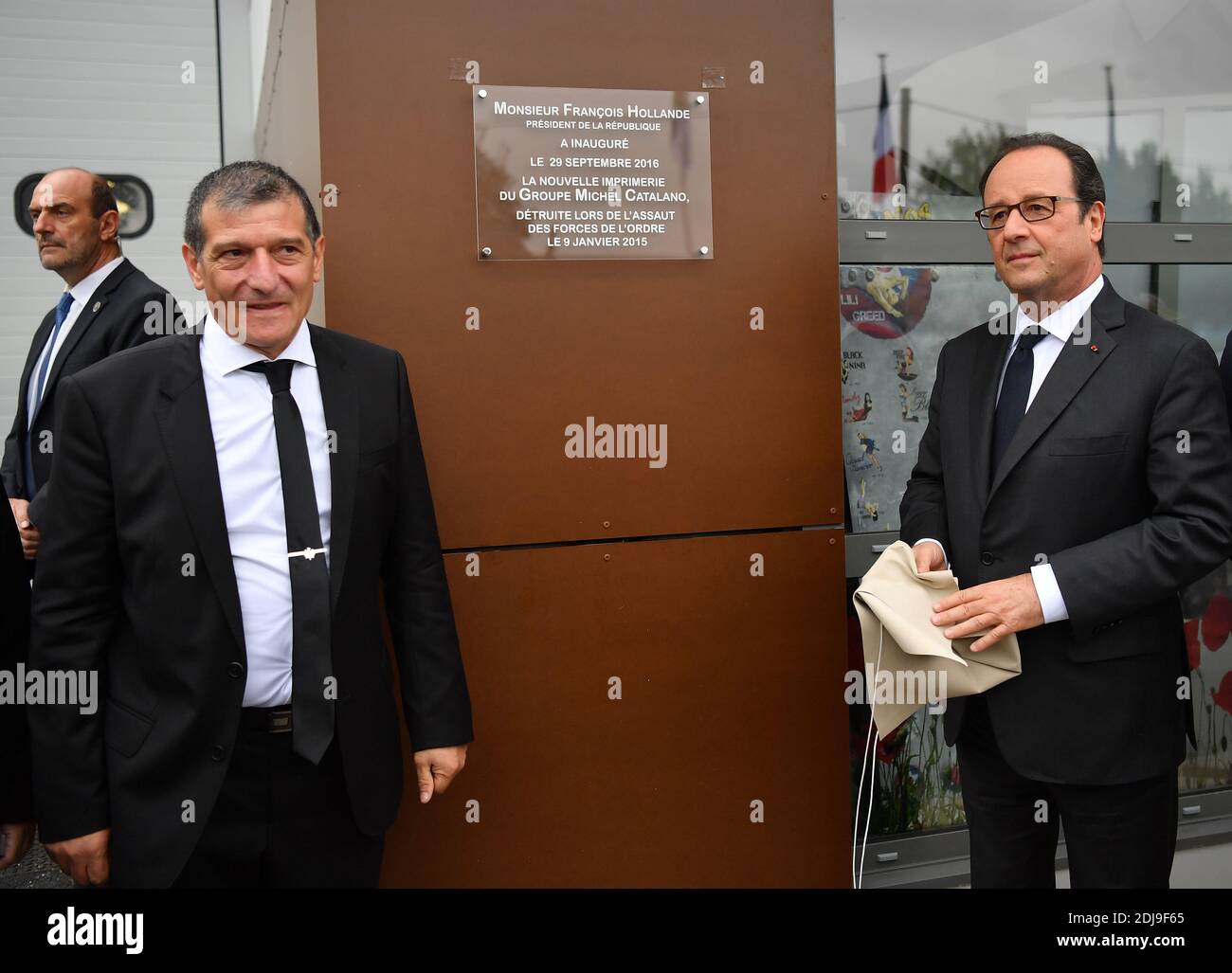 French President Francois Hollande unveils a plaque as printing owner Michel Catalano looks on at Groupe Michel Catalano printing plant duringa ceremony marking its reopening, 18 months after the onslaught against the brothers Kouachi, in Dammartin-en-Goele, near Paris, France on September 29, 2016. On 9 January 2015, Michel Catalano had been held hostage by Cherif and Said Kouachi and released while one of his employees, Lilian Lepere had remained hidden until the intervention of the police who killed the terrorists. Two days earlier, the brothers had killed twelve people at the headquarters Stock Photo