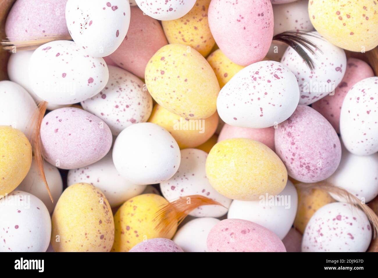 Easter holidays decoration. Funny colourful decorative chocolate Easter eggs background. Close-up. Top view. White yellow pink eggs for Easter treat. Stock Photo