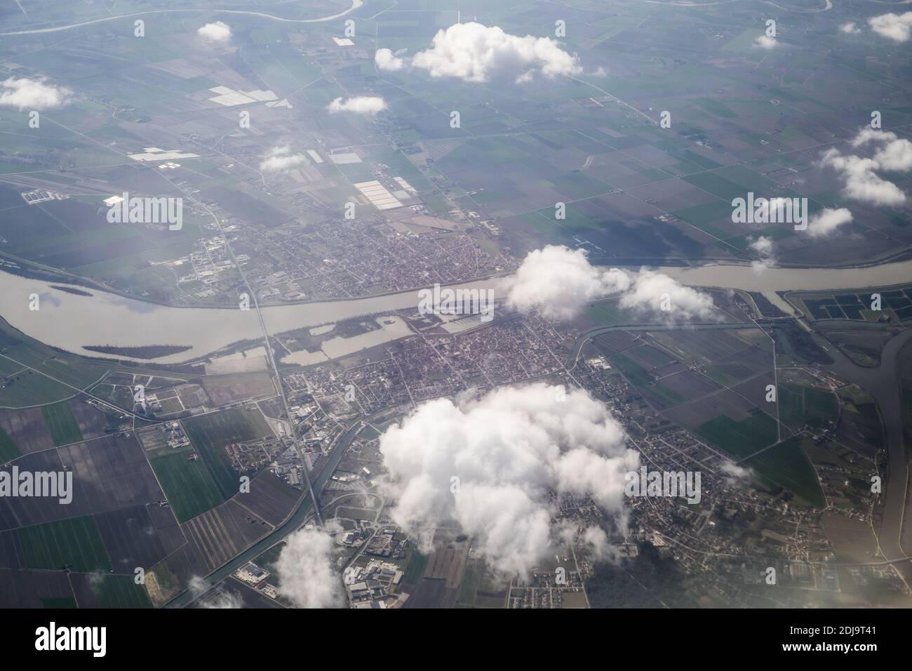 An aerial shot of a landscape with a river and city through the clouds ...
