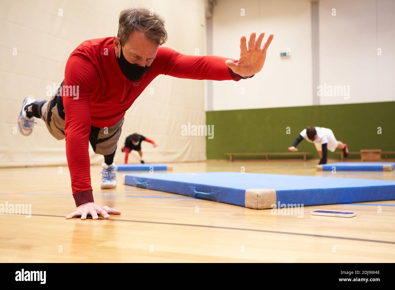 Lahnstein, Germany. 11th Dec, 2020. Sports teacher Oliver Engel shows his  students exercises of functional training in the sports hall of the  Johannes-Gymnasium while wearing a mouth-and-nose protector. However, the  corona pandemic