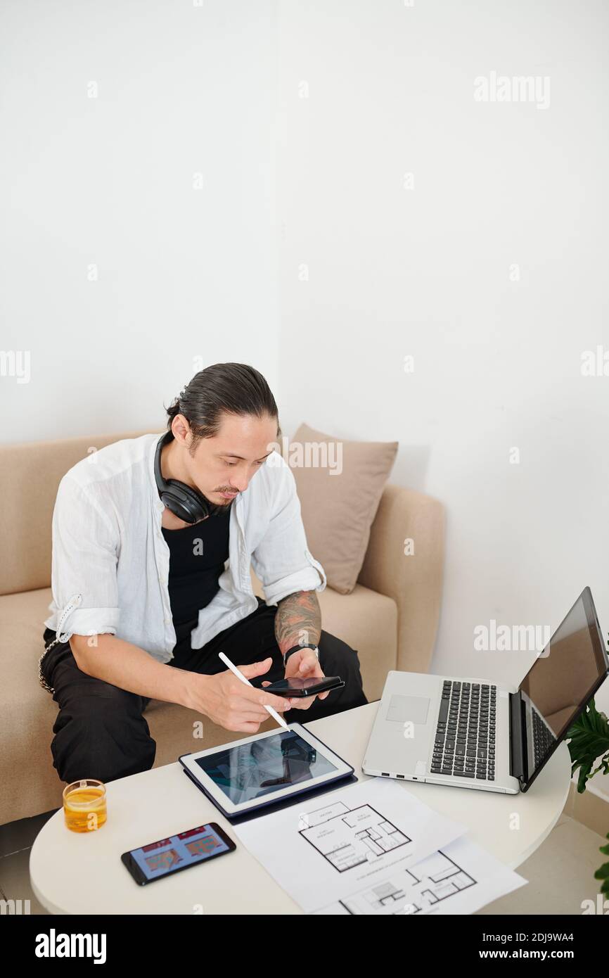 Serious interior designer checking text messages from client when ...