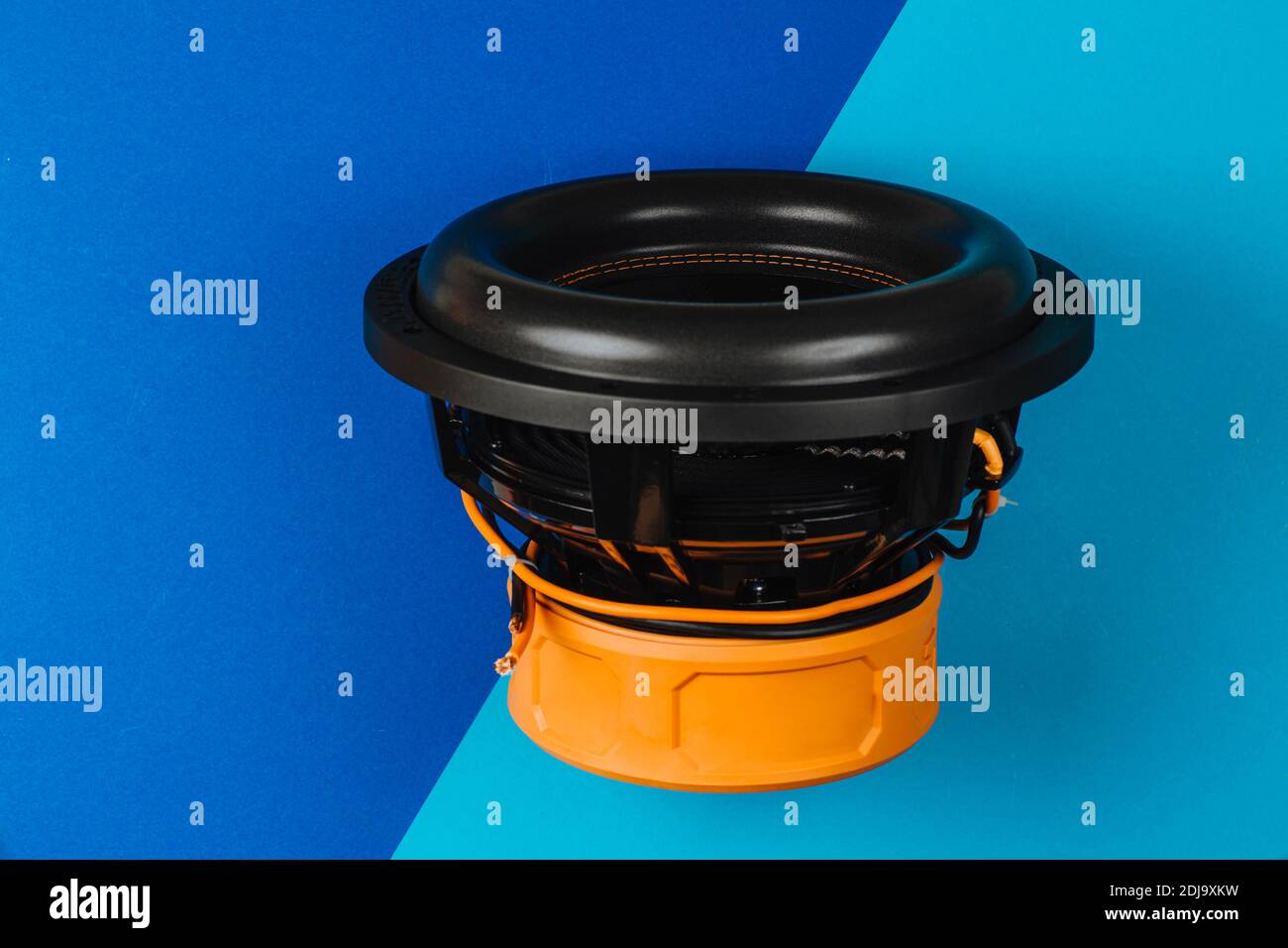 The subwoofer is black on a blue-blue background. Auto sound. Stock Photo