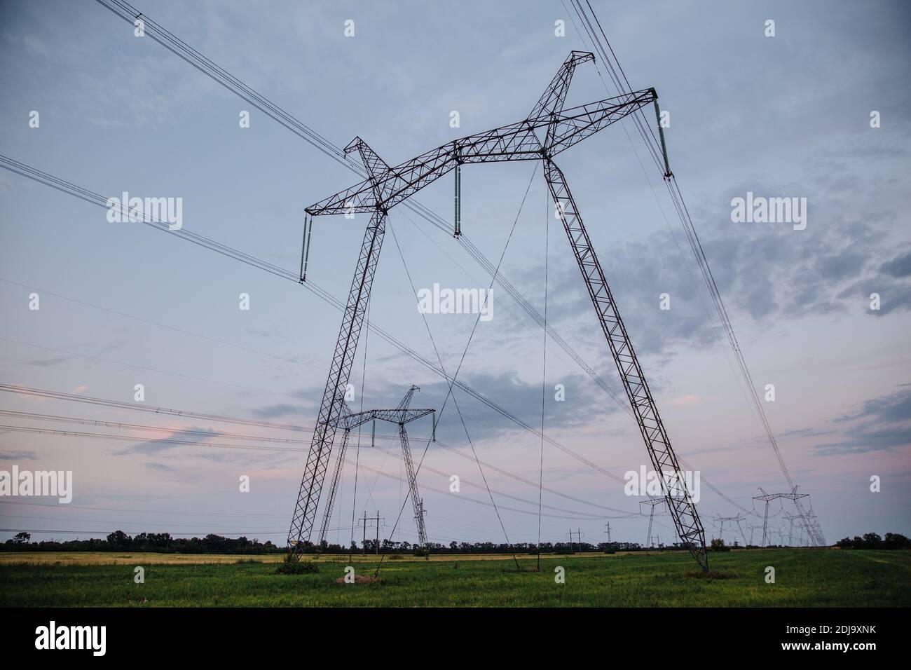 Large metal supports of power lines passing through agrarian fields. High voltage lines Stock