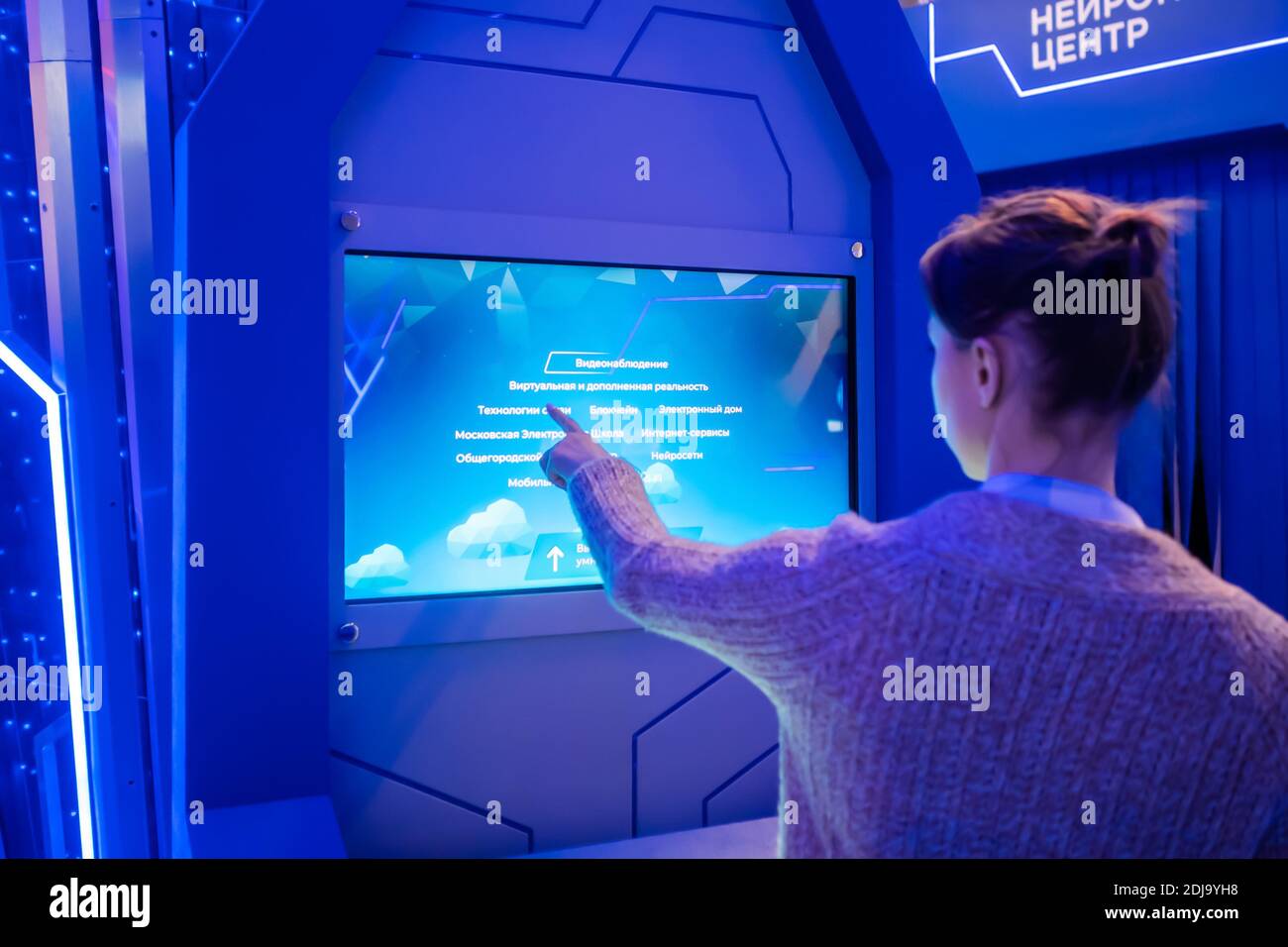 Woman using interactive touchscreen display at modern museum or exhibition Stock Photo