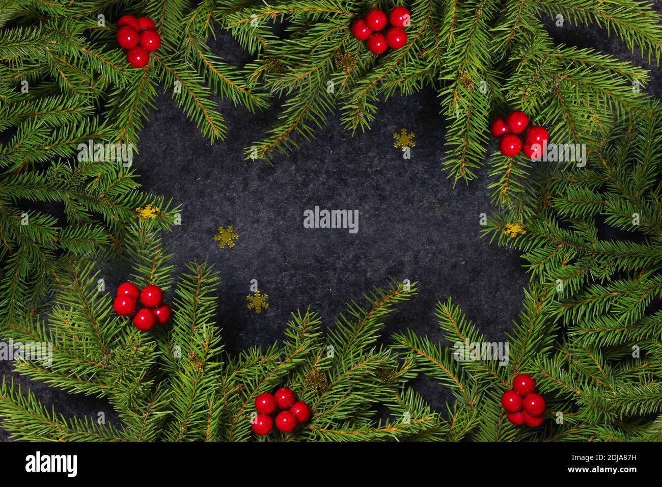 Christmas holiday background with copy space for text. Flat lay, top view. Decorative frame of fir branches and holly berries Stock Photo