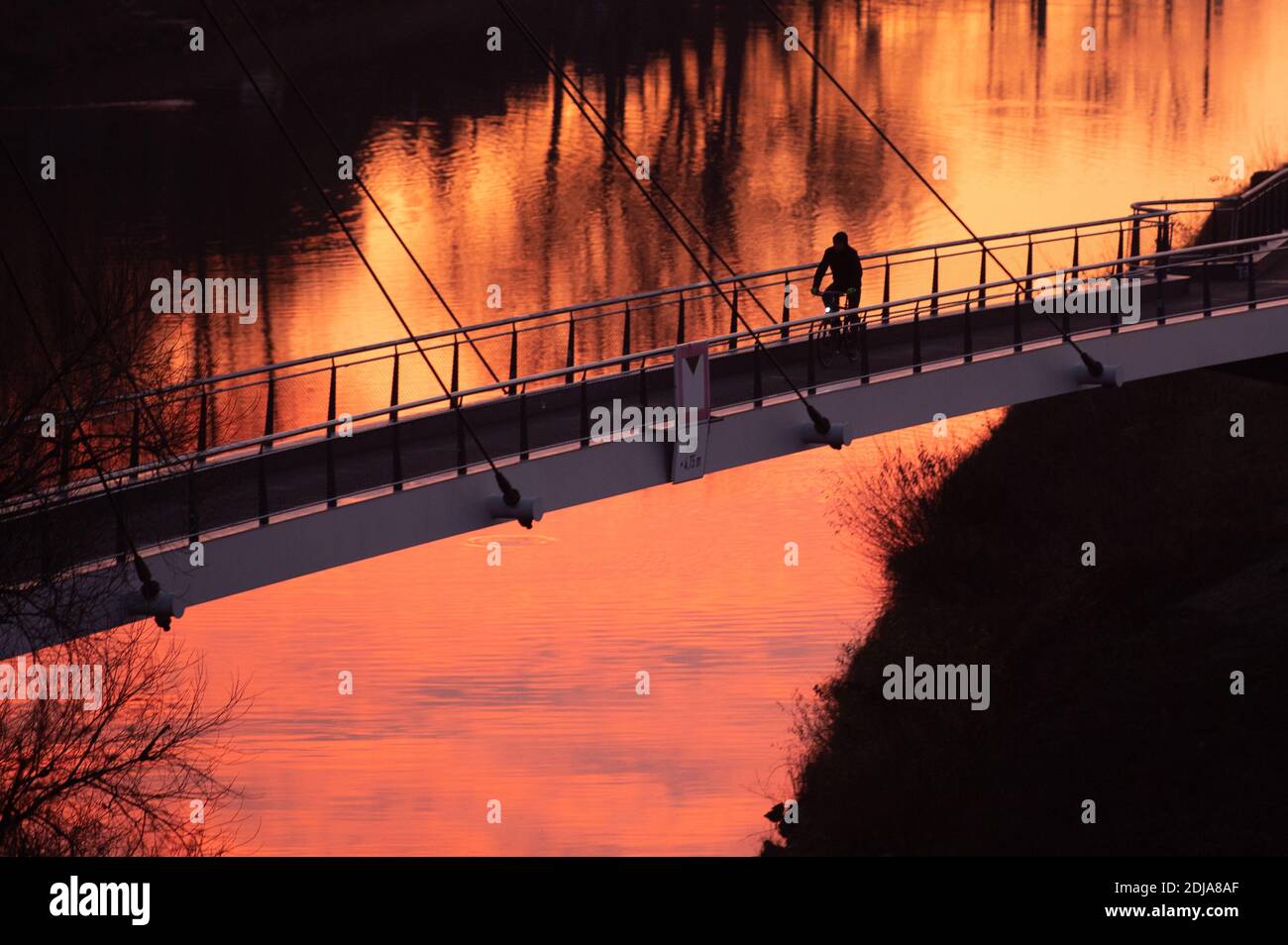 Dresden, Germany. 14th Dec, 2020. A cyclist stands out as a silhouette on the pier bridge at sunrise. Credit: Sebastian Kahnert/dpa-Zentralbild/dpa/Alamy Live News Stock Photo
