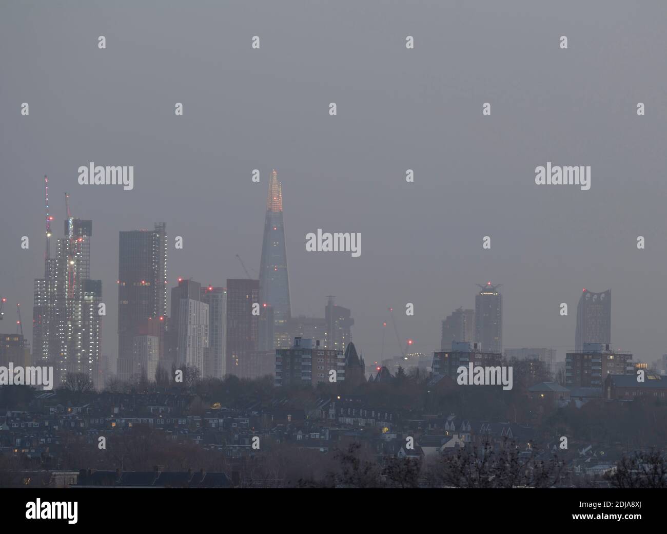 London, UK. 14 December 2020. The Shard London Bridge decorated at the summit floors with multi-coloured Christmas festive lights, and towering above low rise suburban houses in south west London. Credit: Malcolm Park/Alamy Stock Photo